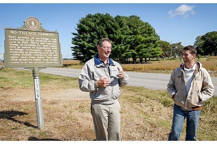 Christian County farmers John and Alexander Young stand in front of the historical marker where Harry Young planted his first commercial crop of no-till corn